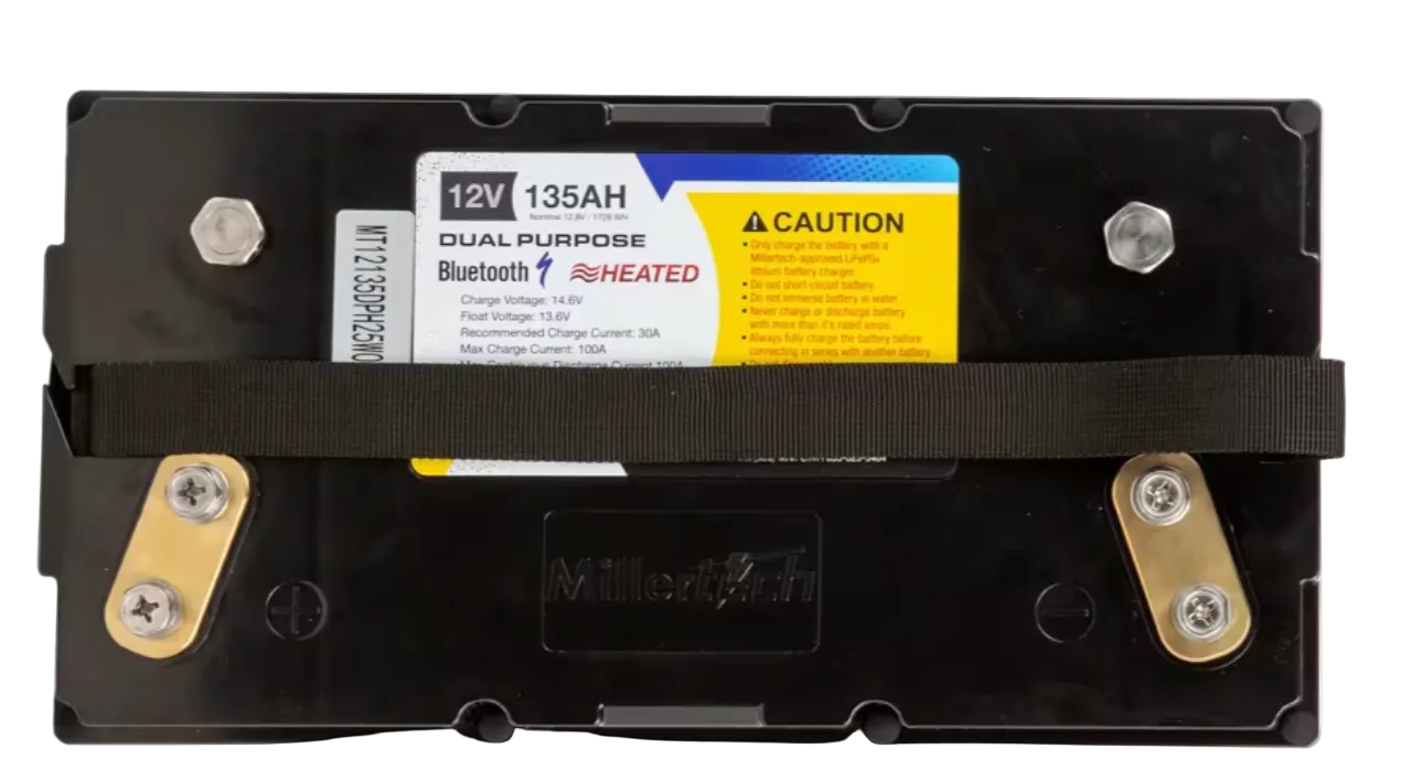 A black dual-purpose heated lithium-ion battery with a black strap across the middle, a yellow and white label, and gold-colored terminal bars on a white background.